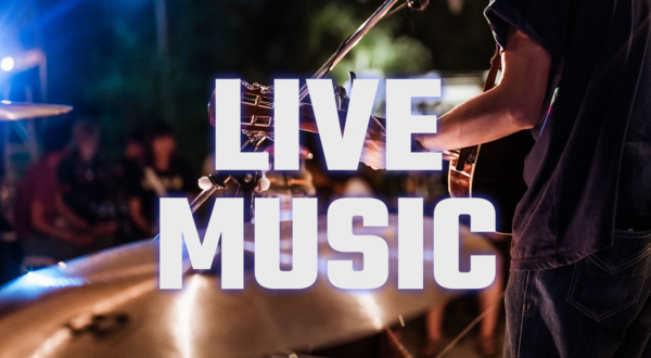 Photo of a guitarist in front of a drummer playing for a crowd.